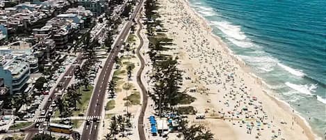 A coastal road with a beach on one side and a cityscape on the other.