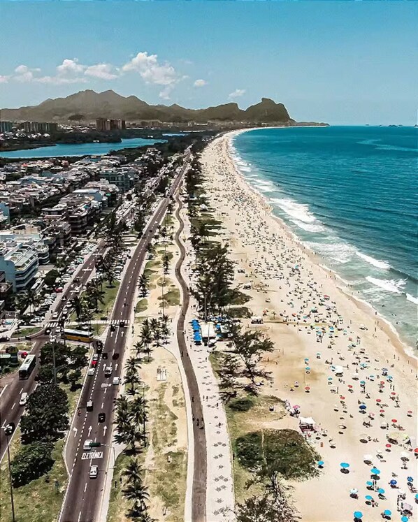 Una carretera costera con una playa a un lado y un paisaje urbano al otro.