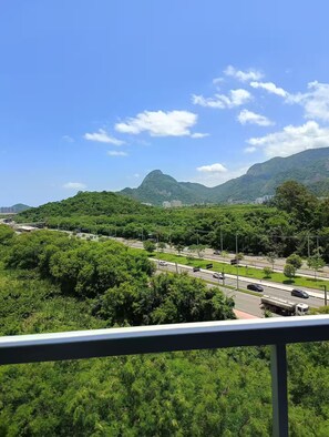 Vista de una autopista con vehículos, rodeada de vegetación verde exuberante y colinas a lo lejos.