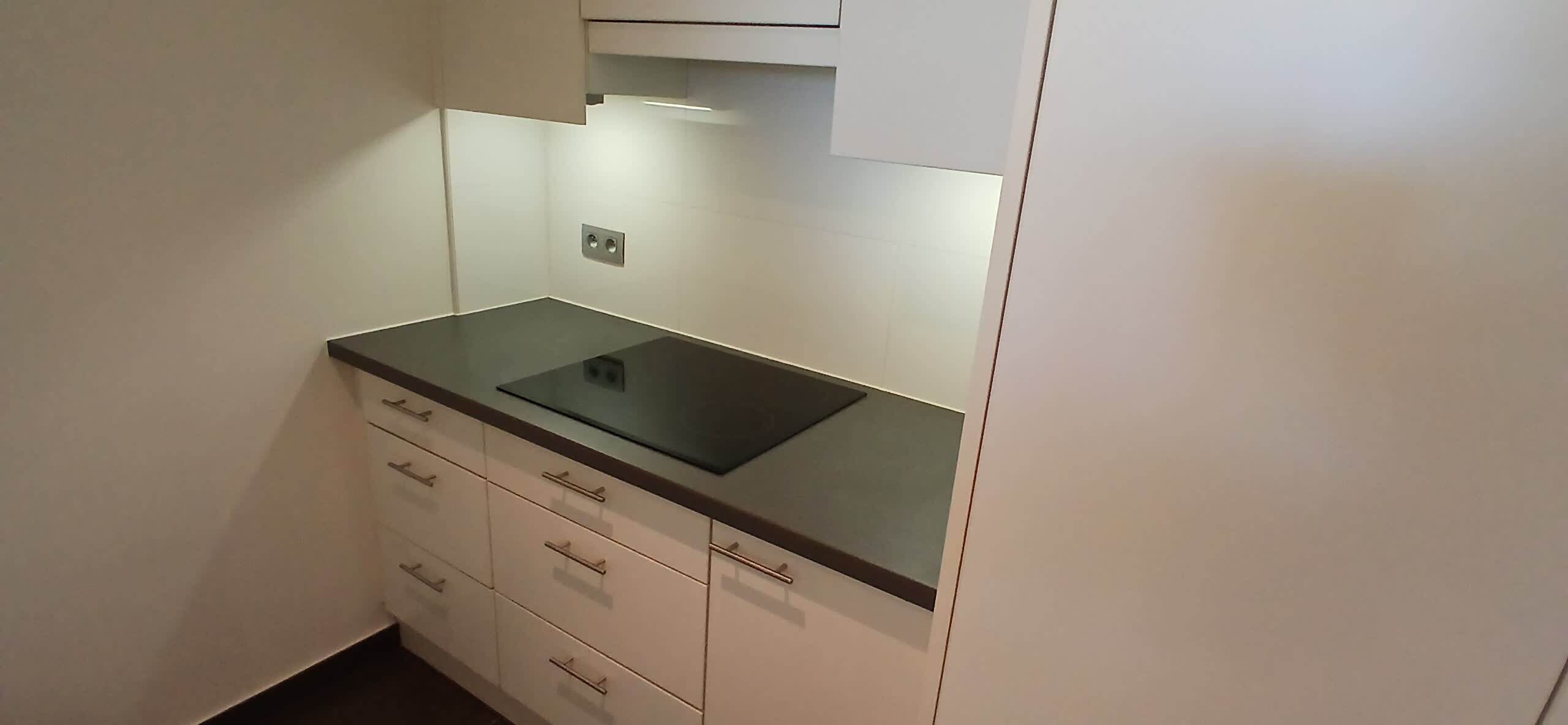 A small kitchen with a black countertop, white cabinets, and a built-in stove.