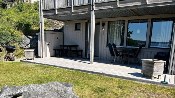 A modern house with a covered porch, outdoor seating, and a large rock in the yard. - 4 Star Holiday Home in Uddevalla (Uddevalla)