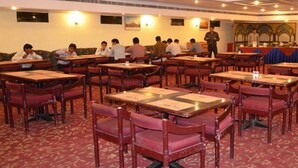 Un comedor con varias mesas y sillas, dispuestas en filas.