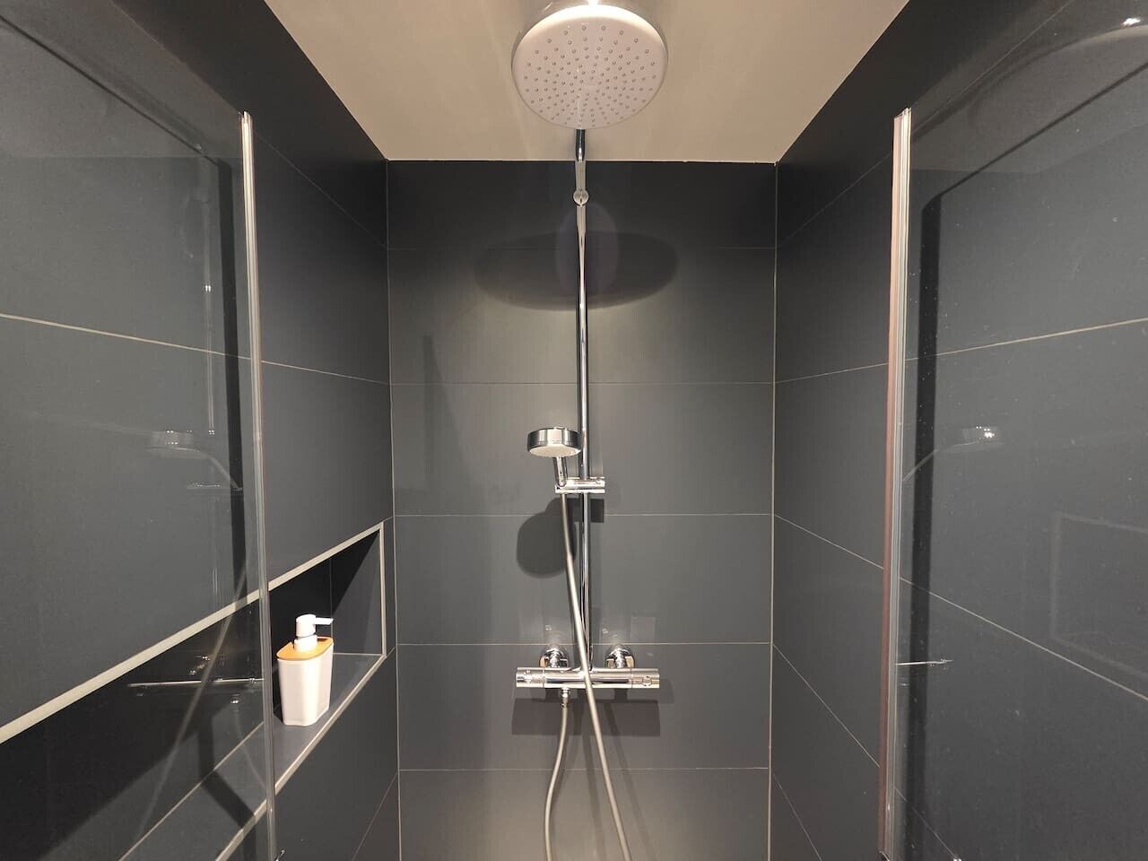 Een moderne douche met een handdouche en een wandmengkraan.