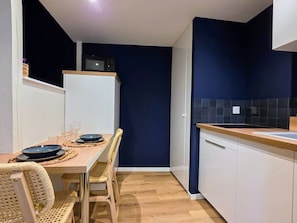 A compact kitchen with a dining area, featuring a microwave, a sink, and a dining table set with plates and glasses. - Spa Suite 15 minutes from Strasbourg (Schiltigheim)