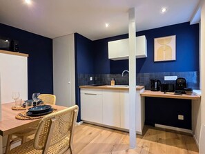 A compact kitchen with white cabinets, a wooden countertop, and a dark blue backsplash. - Spa Suite 15 minutes from Strasbourg (Schiltigheim)
