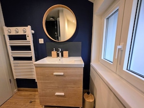 A bathroom with a white vanity, a round mirror, and a window. - Spa Suite 15 minutes from Strasbourg (Schiltigheim)