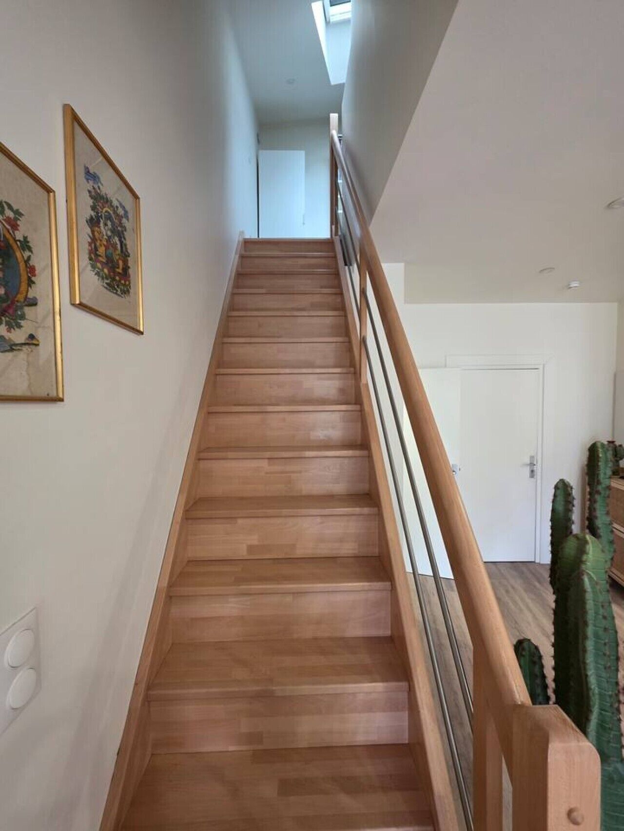 Eine Holztreppe mit Glastrennwand, die zu einer weißen Tür führt.