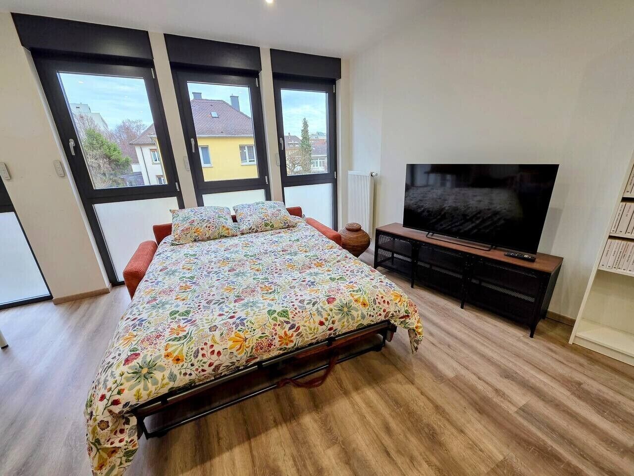 Ein Schlafzimmer mit einem Bett, einem Fernseher und großen Fenstern.