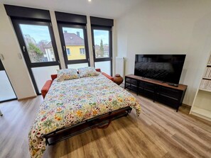 Ein Schlafzimmer mit einem Bett, einem Fernseher und großen Fenstern.