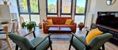 A modern living room with a sofa, two armchairs, a coffee table, and a television.