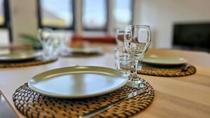 Een eettafel gedekt met borden, bestek en een glas.