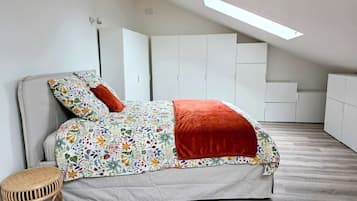 Ein Schlafzimmer mit einem Bett, einem kleinen Hocker und einem Oberlicht.