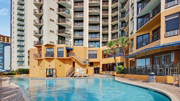 Um edifício residencial com vários andares e uma piscina.