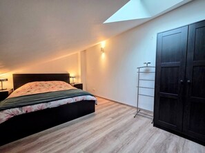 A bedroom with a bed, a wardrobe, a skylight, and a nightstand with a lamp. - Charming 55-square-meter duplex, 15 minutes from Strasbourg (Schiltigheim)