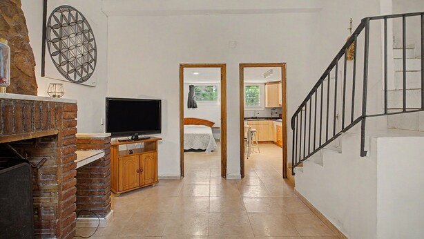 A hallway with a television, a fireplace, and a staircase leading to another room.