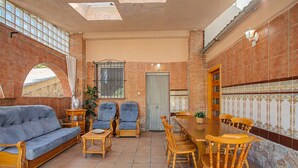 A furnished patio with a sofa, chairs, a dining table, and a tiled floor.