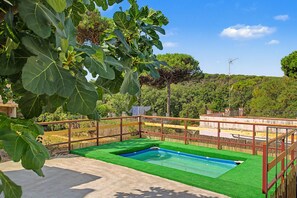 A swimming pool with a wooden deck and a view of a forested hill.