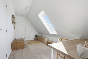 Ein modernes Schlafzimmer im Loft-Stil mit Dachfenster, integriertem Kleiderschrank und einer gemütlichen Sitzecke.