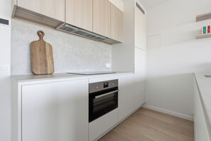 Eine moderne Küche mit weißen Schränken, einem eingebauten Backofen und einem Holzschneidebrett auf der Arbeitsplatte.