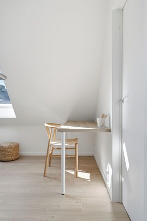 A small, modern room with a sloped ceiling, a wooden desk, a chair, and a white door. - Luxury Duplex "Ondune" - Duinpark Oostduinkerke (Koksijde)