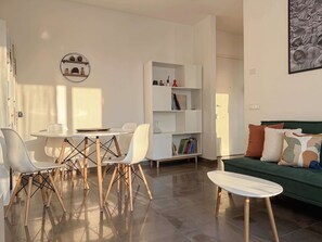 A modern living room with a dining area, a bookshelf, and a green sofa. - Casa Bonvicino, Città Studi (Milano)