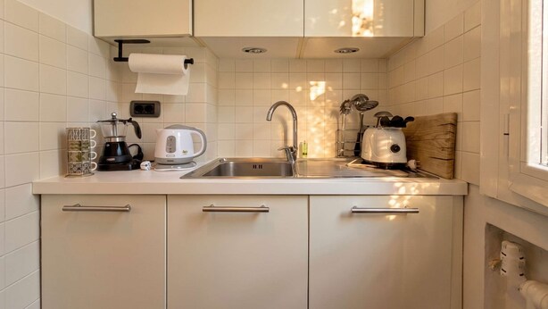 Eine Küche mit weißen Schränken, einer Edelstahlspüle, einer Kaffeemaschine, einem Wasserkocher und einem Toaster.