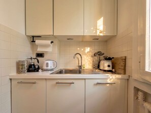 A kitchen with white cabinets, a stainless steel sink, a coffee maker, a kettle, and a toaster. - Casa Bonvicino, Città Studi (Milano)