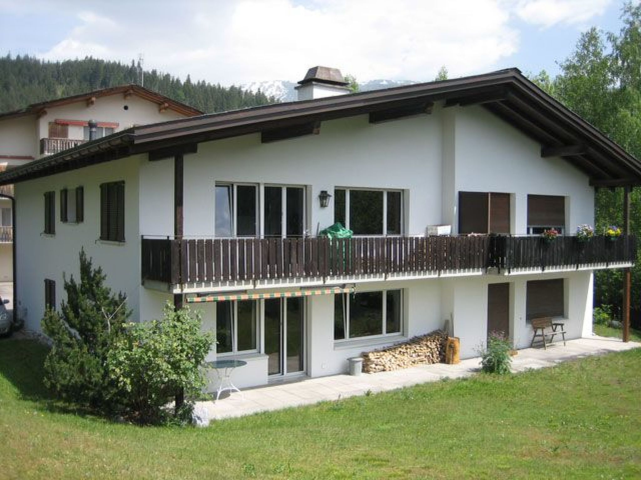 Ein zweigeschossiges Haus mit Balkon, großen Fenstern und einem gepflegten Rasen.