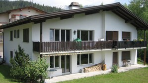 Ein zweistöckiges Haus mit Balkon, großen Fenstern und einem gepflegten Rasen.