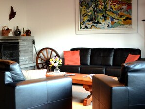 A living room with a black leather sofa, a wooden coffee table, and a fireplace with decorative items. - Surrieven / Friz, (Laax Dorf), 240 by Interhome (Laax)