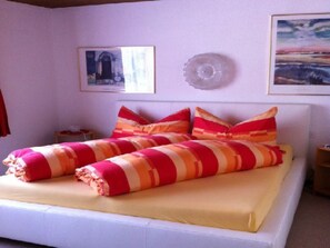 A bed with striped bedding, a bedside table, and wall art. - Surrieven / Friz, (Laax Dorf), 240 by Interhome (Laax)