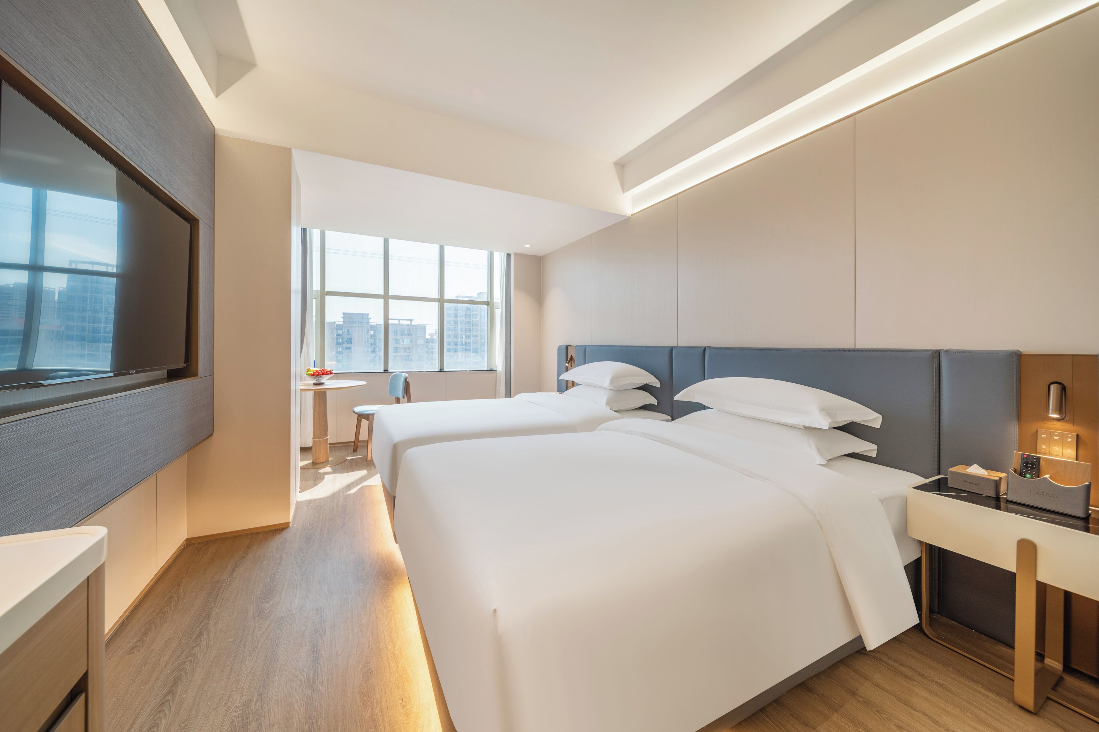 A hotel room with a large bed, bedside tables, a desk, and a window with a city view.