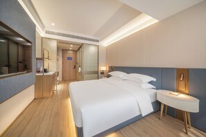 A hotel room with a large bed, bedside table, and a mirror. - Poltton Century Hotel (Shenzhen International Exhibition Center Buyong Metro Station Branch) (Shenzhen)