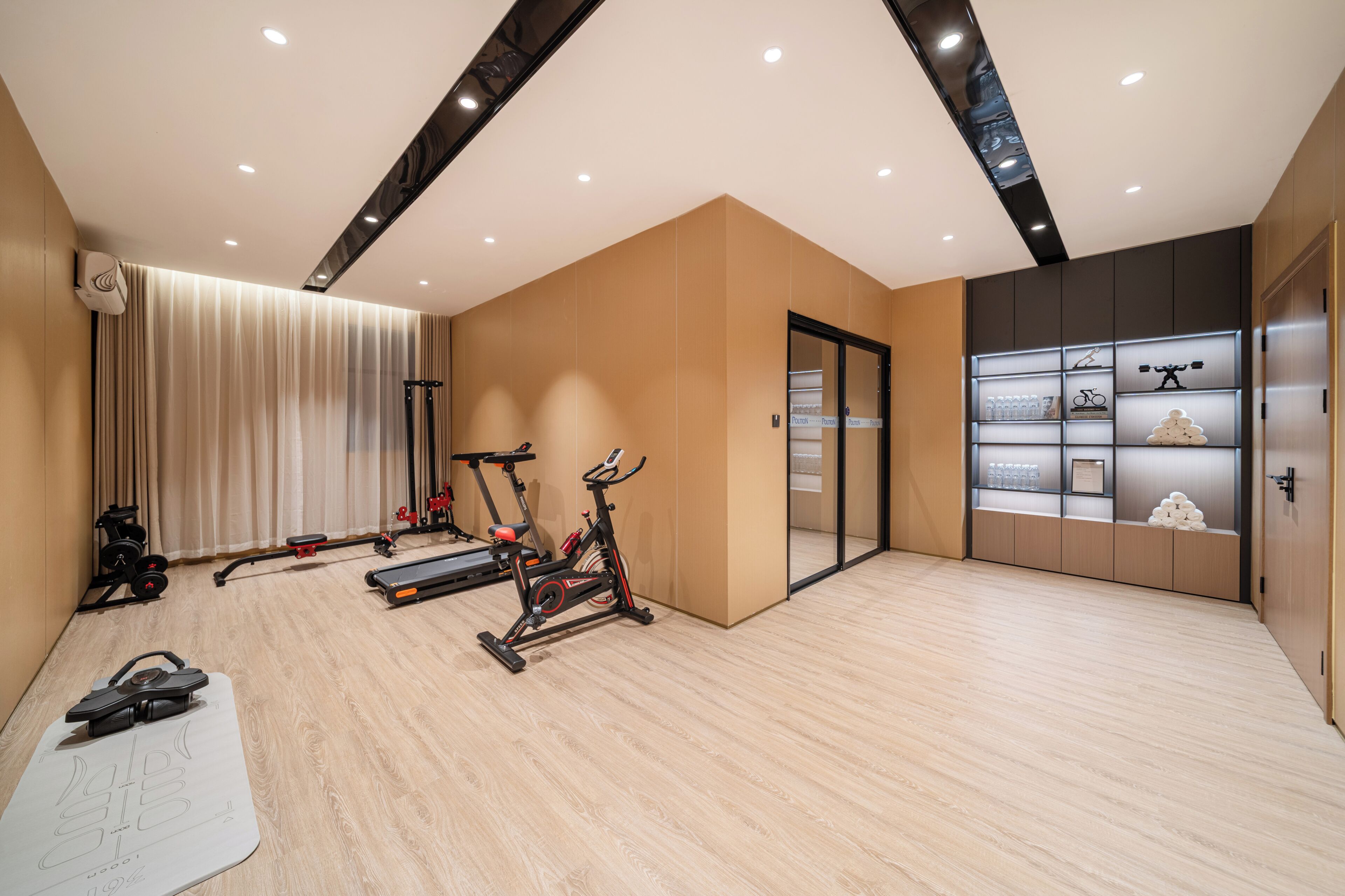 A modern gym with exercise equipment, a large mirror, and a wall with storage cabinets.