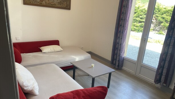 Quarto com duas camas, uma mesa e uma janela com cortinas.
