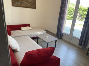 Ein Zimmer mit zwei Betten, einem Tisch und einem fenster mit Vorhängen.