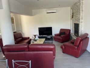 Ein Wohnzimmer mit roten Ledersofas, einem Flachbildfernseher, einem Kamin und einer Steinwand.