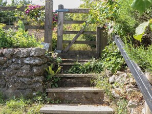 A stone staircase leading up to a wooden gate, surrounded by greenery and a stone wall. - Lustleigh Mill Barn (Newton Abbot)