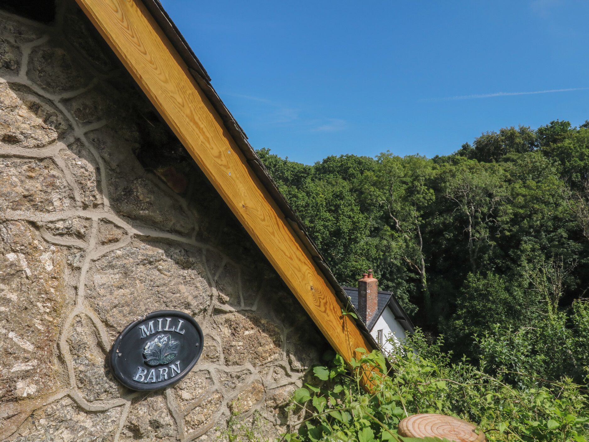 A stone building with a wooden beam and a sign that reads 'MILL BARN'.