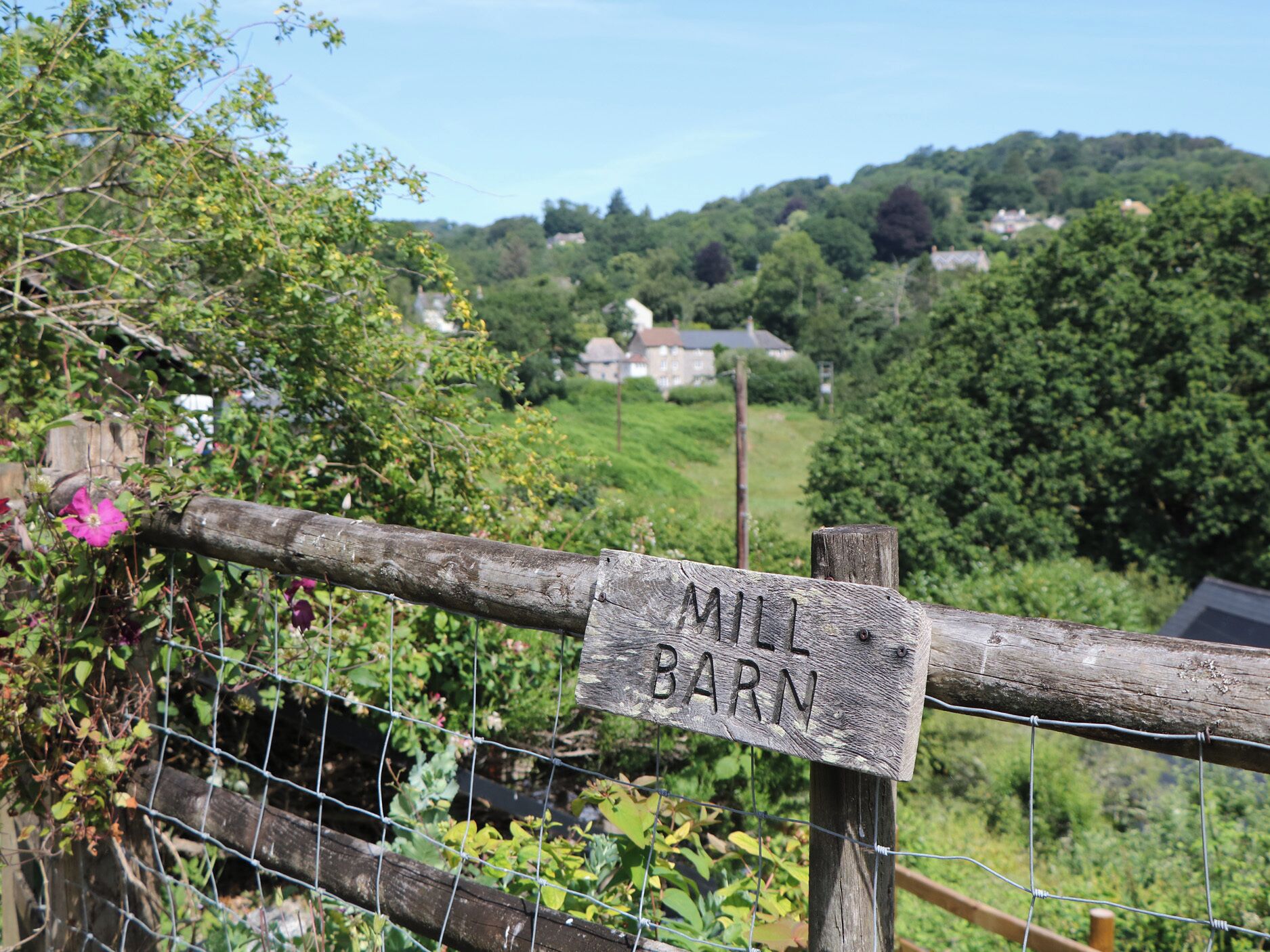 A wooden fence with a sign that reads 'MILL BARN.'
