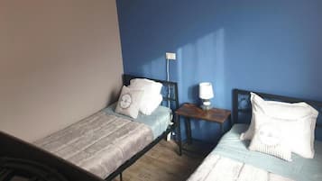 A room with two single beds, a bedside table with a lamp, and a wall socket.