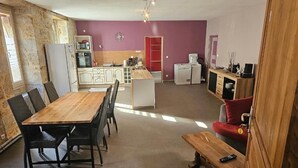 Een compacte woonruimte met een eettafel, stoelen, een keuken met inbouwapparatuur en een rode bank.