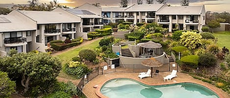 A residential complex with multiple apartment buildings, a swimming pool, and landscaped gardens.