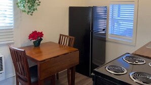 Une cuisine de taille réduite comprenant une table à manger, des chaises, un réfrigérateur et une cuisinière.