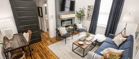 A modern living room with a sofa, coffee table, and a TV mounted on the wall.