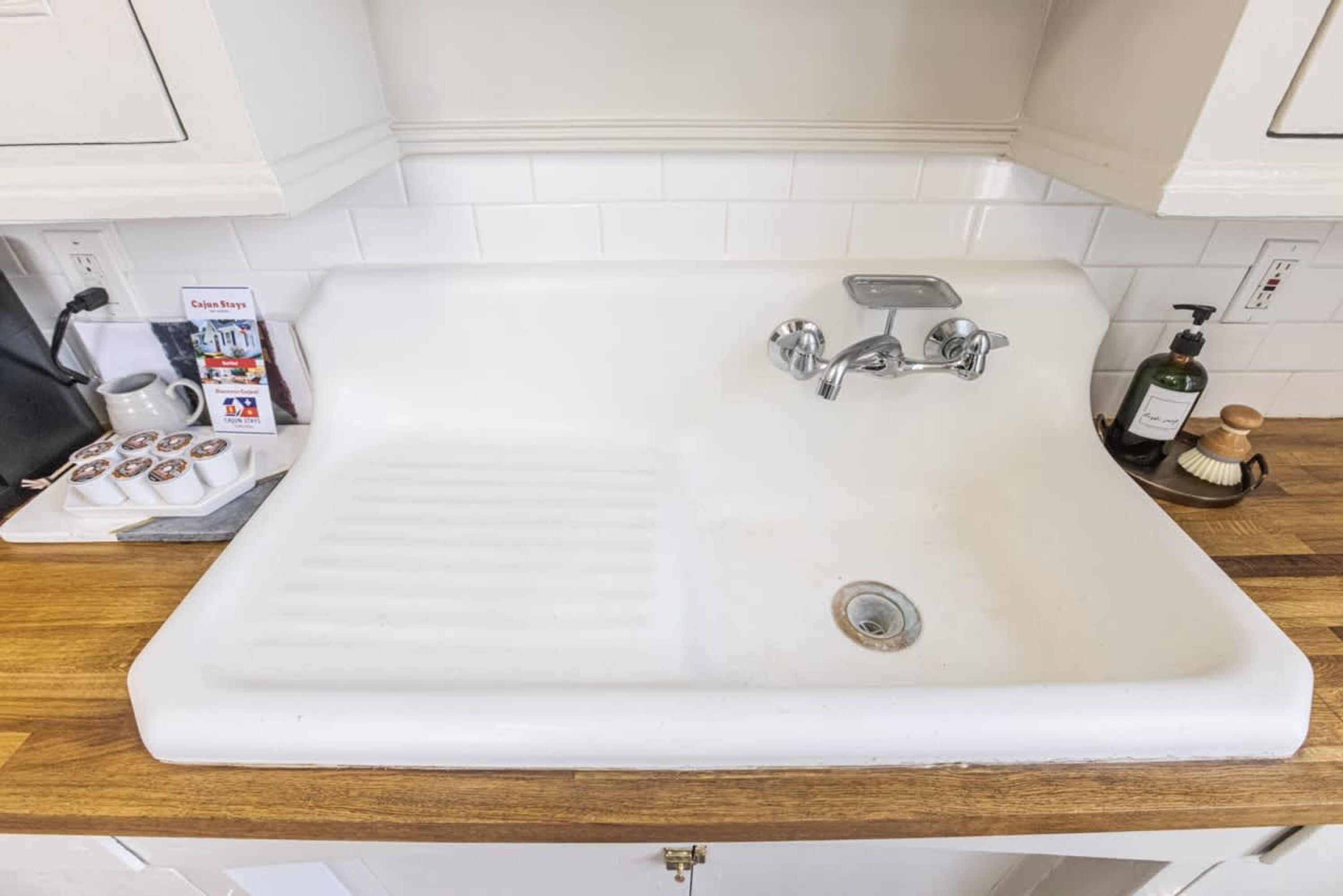 A white bathroom sink with a single faucet, a soap dispenser, and a toothbrush holder on the countertop.