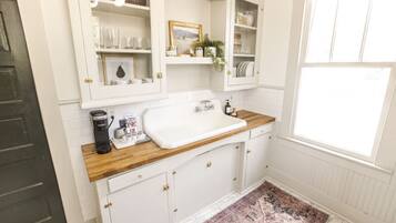 A kitchen with white cabinets, a wooden countertop, a sink, and a window.