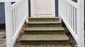 A front door with a sign, a white picket fence, and a set of stone steps leading up to it. - Modern Cajun Stay 1BR Near Festivals Food (Lafayette)