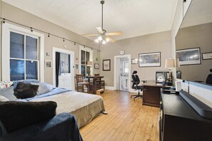 Ein Schlafzimmer mit einem Bett, einem Schreibtisch, einem Stuhl und einem Deckenventilator.