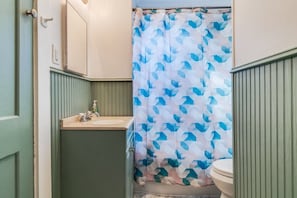 Un baño con cortina de ducha, lavamanos e inodoro.